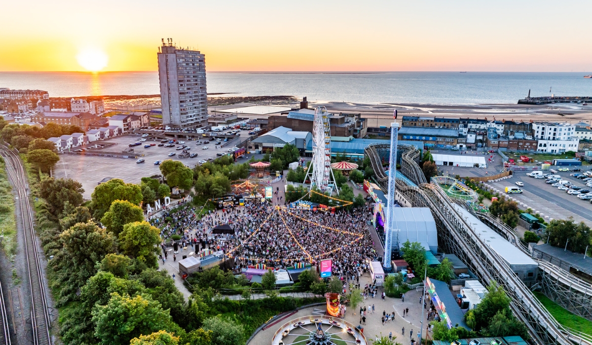 drone view of Dreamland outdoor amusement park with sea in the distance at sunset